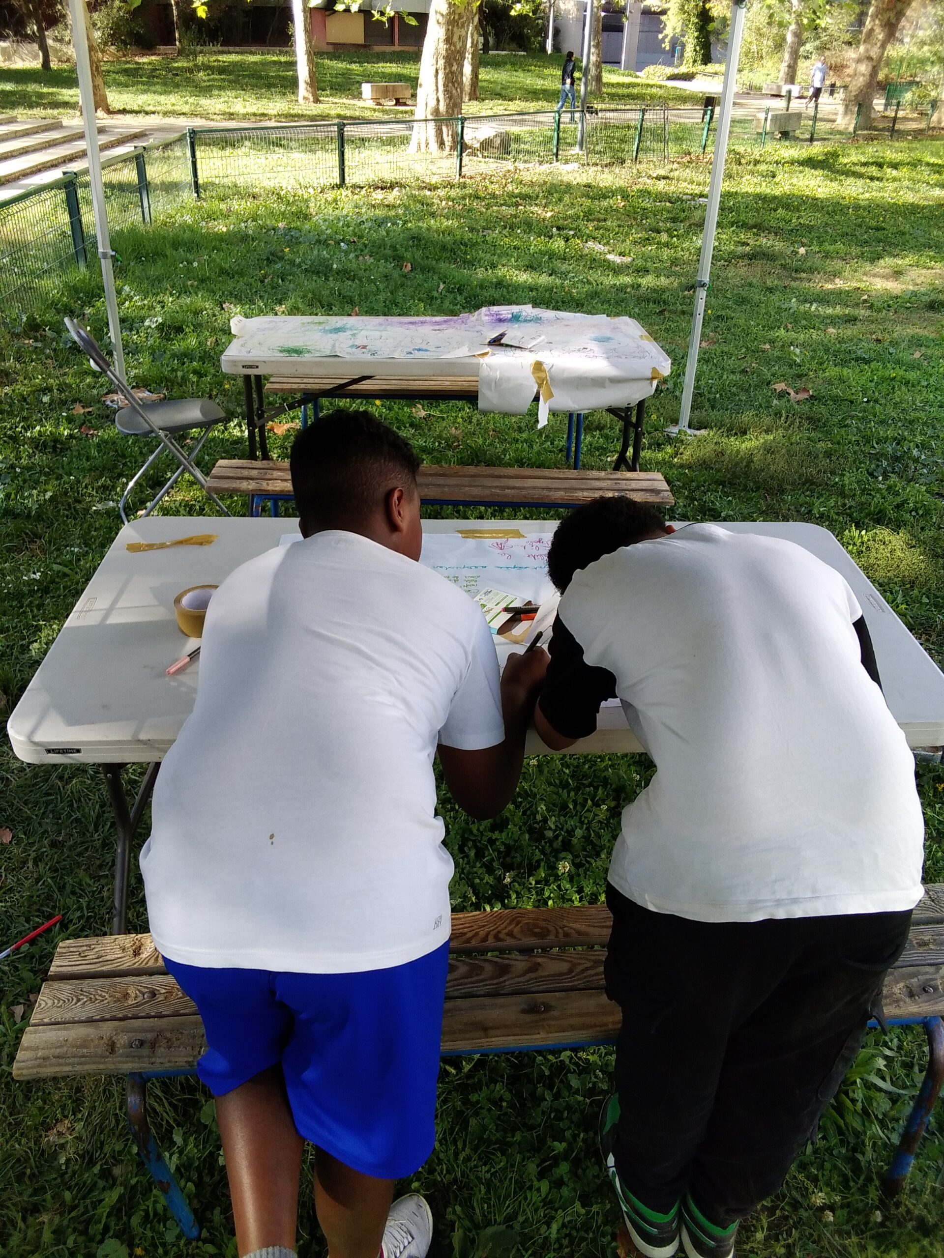 2 jeunes de dot à l'extérieur penchés sur une table de jardin